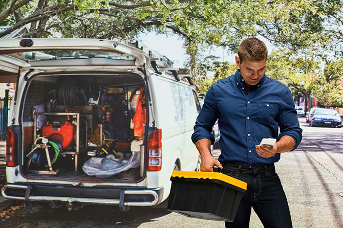 Handwerker mit Koffer vor Transporter